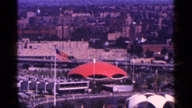 1964: the skyline of an american city with a flag blowing in the foreground