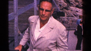 1964: men in jackets and glasses talk to the camera as they walk up stairs