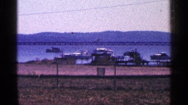 1964: a station wagon is parked near a dock where small boats sit in the water