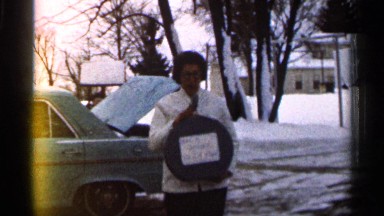 1966: woman retrieves a back at home sign made out of a bag from the trunk