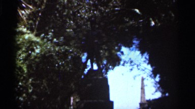 1966: tall statues in the background on a luscious pathway covered with plants.
