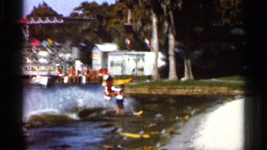 1966: vacationers frolic on and around deep blue water, fronted by boats
