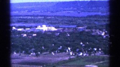 1965: a beautiful long shot view of forest and a city at the behind