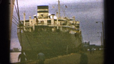 1965: men kick a soccer ball next to a large ship tied to a dock DULUTH