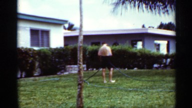 1963: two boys play with sprinkles on the front yard of a house