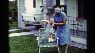 1963: the baby sit on the chair and the lady helped to the child