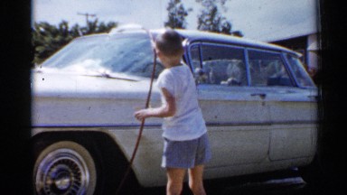 1958: a little boy cleaning his car using water by the pipe at the front