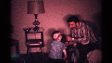 1958: man playing with a young child by roughhousing him with his fast moving