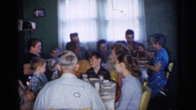 1958: many peoples are sited near a dining table and chat each other