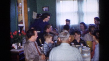 1958: big family enjoys dinner around the table while being served by the mother