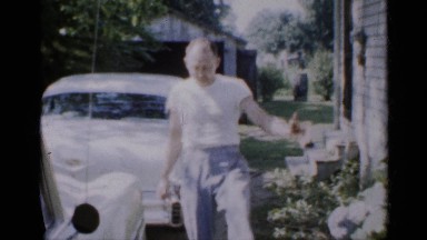 1958: a man in the road dancing happy while walking and reached near car