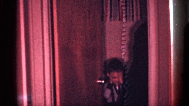 1958: Woman in Checked Dress Takes Cigarette Near Small Boy in Room