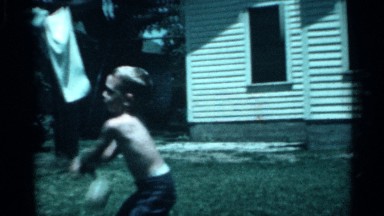 1958: boy strongly throws ball toward boy wildly swinging bat in sunny yard