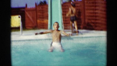 1963: A Boy Slides Down Sloped Poolside and Swims Across to the Other Side