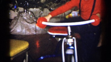 1959: woman walking pass as little boys hops on on bicycle in front