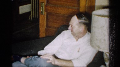 1959: a old man watching the child and he sit in chair watch the baby playing