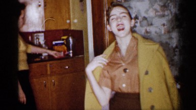 1959: young woman in bright yellow coat waves goodbye and departs her home