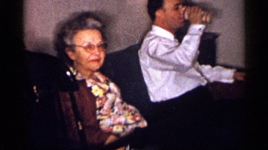 1959: older woman is seated by man wearing white shirt drinking from can