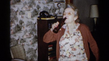 1959: An Elderly Woman Drinks an Alcoholic Beverage from a Glass Bottle in Michigan