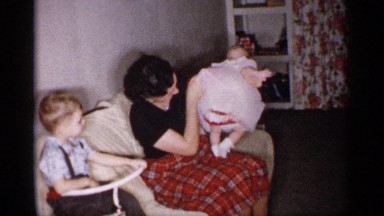 1959: mother check the baby dress and to laugh it correct size