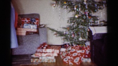 1959: a family of three looking at presents on a couch in a living room