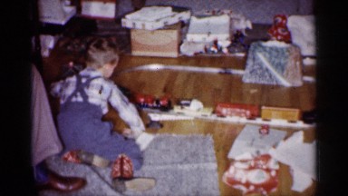 1959: excited young boy plays with his new toy train set MICHIGAN