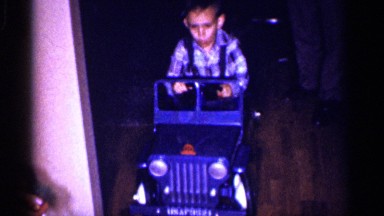 1959: little boy driving a toy power wheel jeep indoors. MICHIGAN