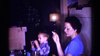 1959: family gathered around with some smoking and a child playing MICHIGAN