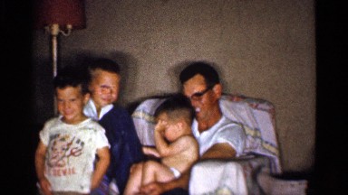 1959: man wearing eyeglasses sits with three boys who are different ages