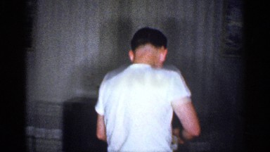1959: a man dressed in a t shirt and pants walks across a living room MICHIGAN