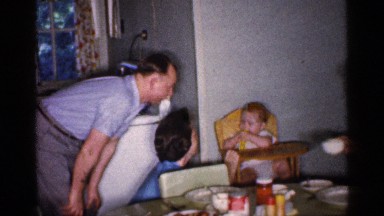 1959: a cute little baby sits in the wooden highchair while chewing