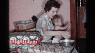 1955: a mother gives a crying toddler a sponge bath while it sits in her lap