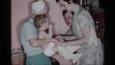 1955: the small baby change the dress four women near to chair bench child