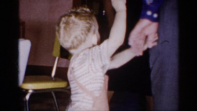 1955: little kid being pampered by his grandfather, waving handing happily.