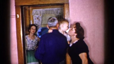 1955: mother, grandmother, and grandfather showers a little boy with kisses