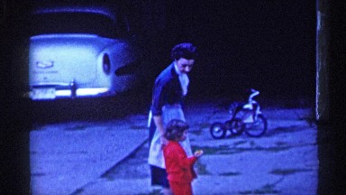 1955: a child and women walk to come house child only stop the street empty