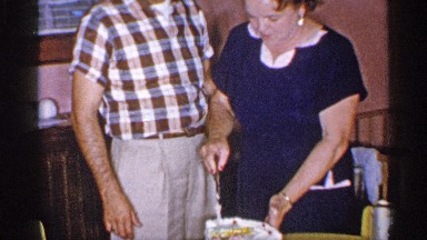 1955: Man and Woman Hold Knife to Cut Decorated Cake as Child Appears