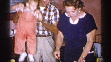 1955: father picks up his son so he can cut his birthday cake,while mother holds
