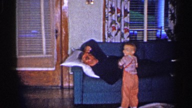 1955: a male toddler wakes his grandfather laying on the couch