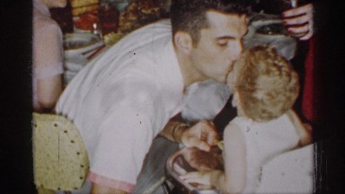 1955: man kissing a child, sitting around a table at a meal NEW YORK