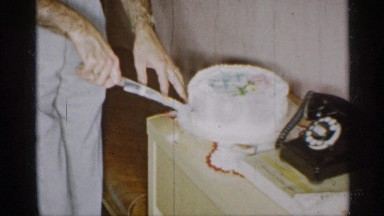 1955: a man cutting cake at his home in the morning time and a telephone near to