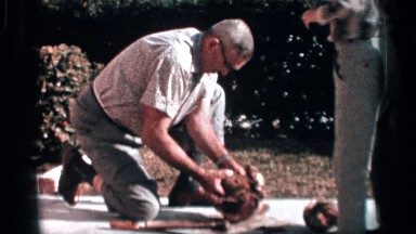 1958: an older man peels a coconut in the sunshine. FLORIDA