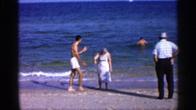 1958: a man and a woman on the sea shore standing on the sea and another man