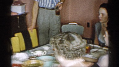 1955: family gathered around dining table enjoying each others company. NEW YORK