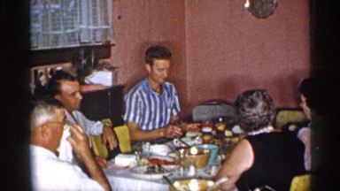 1955: many peoples are sited near a dining table and chat each other