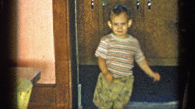 1955: a cute baby boy is walking into a room smiling wearing his mini clothes
