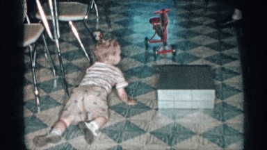 1955: a baby trying to open a box doing something with the box at the dining
