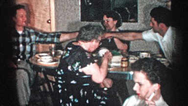 1955: family gathering around a table together for coffee while watching