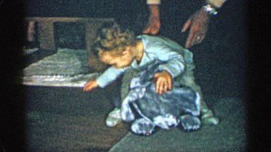 1955: little child playing with his small rocking toy while learning how to walk