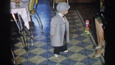 1955: interior with dressed-up child, adult's legs and furniture. NEW YORK